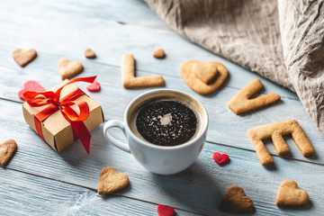 Cup of coffee and a message from a sweet cookie in the form of the word love. Romantic Valentine's day gift