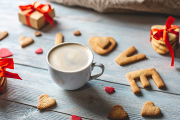 Cup of coffee and a message from a sweet cookie in the form of the word love. Romantic Valentine's day gift