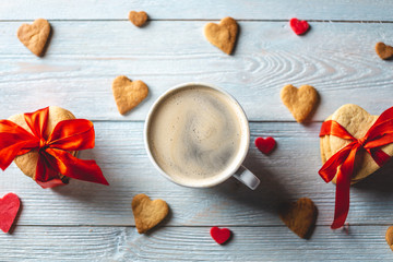 Cup of coffee and a sweet gift of cookies tied with red ribbon in the form of hearts. Romantic Valentine's day gift
