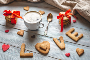 Cup of coffee and a message from a sweet cookie in the form of the word love. Romantic Valentine's day gift