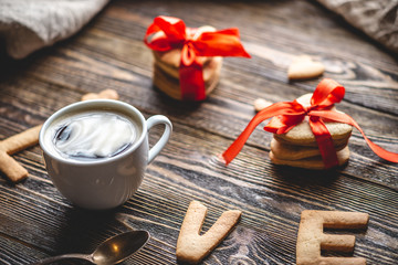 Cup of coffee and a message from a sweet cookie in the form of the word love. Romantic Valentine's day gift