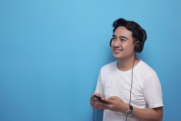 Fototapeta premium Young Asian man listening to music on his smart phone