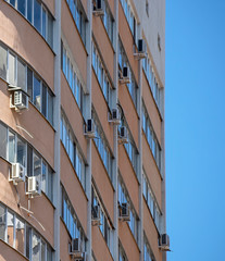Modern multistory residential building with wall mounted air conditioning units against a blue sky