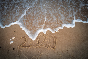 2020 in Sand geschrieben wird überspült von Welle