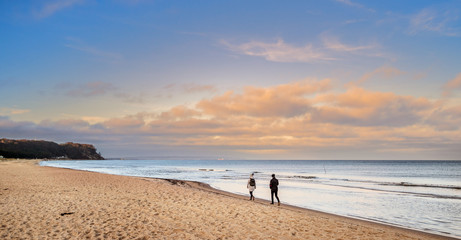 Frau und Mann spazieren am Meer, Ostsee vor orangen Wolken