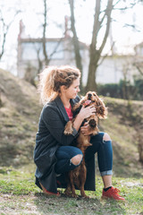 Attractive happy young curly woman hugs her favorite cocker spaniel dog