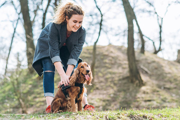 Attractive young curly woman with her pet dog on a walk in the park