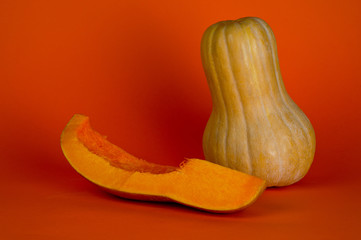 Ripe elongated pumpkin, a very healthy product, shot on a bright orange background