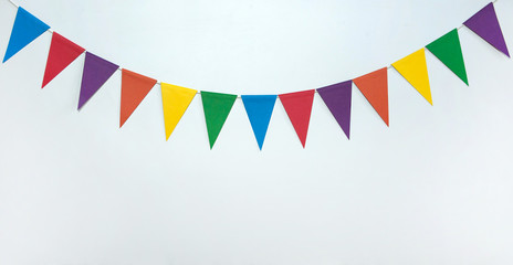 The concept of the birthday in the style of minimalism. A garland of triangular multicolored paper flags on a white background. Free space.