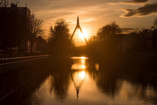 Mulhouse - France - 15 January 2020 - panorama with silhouette of suspended bridge under the channel with reflection by sunset