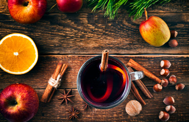 Christmas hot mulled wine with spices, cinnamon sticks, anise, orange, nuts and apples on a old...