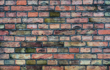 Very old red brick wall, on which defects were partially manifested due to long time and weather conditions, partially changed color