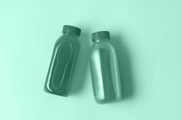 Bottles with drink or smoothies on neo mint background. Flat lay, top view.