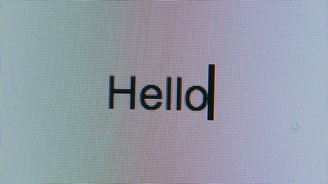 Cursor Typing Out The Word Hello Flashing Cursor On Computer Screen Bright White Blank Page. Thinking Of Something To Write. Empty Page Writers Block