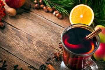Christmas hot mulled wine with spices, cinnamon sticks, anise, orange, nuts and apples on a old wooden background. 