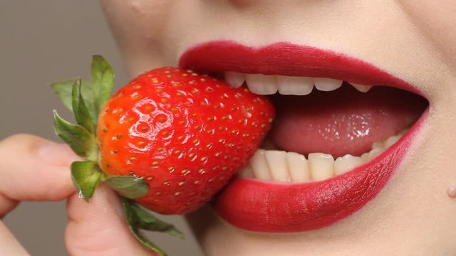 Sexy Woman Eating Strawberry. Close up view of Sensual Red Lips. 
