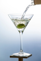 White wine pouring from a bottle into a glass with olives