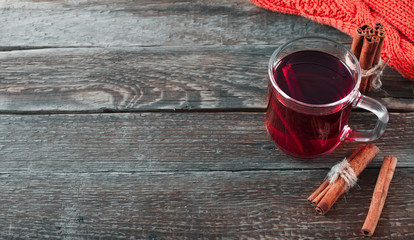Mulled wine with cinnamon sticks and woolen scarf on a old wooden background. Autumn background. Christmas background.