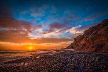  Beautiful beach sunset with sunlit bluffs and a rocky shore © Forest2Sea