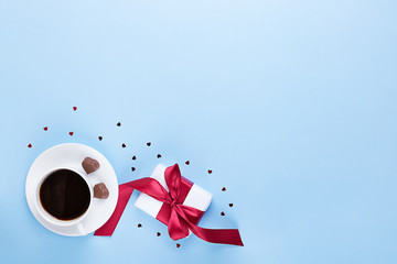 Banner of Valentine's Day. A Cup of coffee, a gift box and a heart-shaped chocolate on a blue...
