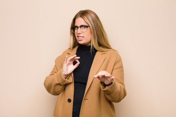 young blonde woman feeling disgusted and nauseous, backing away from something nasty, smelly or...