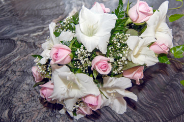Ramo de rosas de color rosa y lirios blancos sobre una mesa de marmol gris