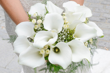 Manos de una novia cogiendo un ramo de flores de alcatraz blanco