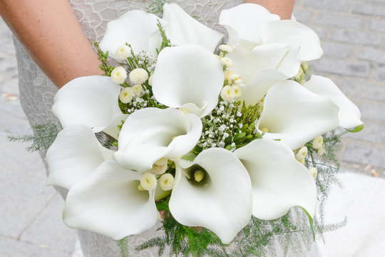Manos de una novia cogiendo un ramo de flores de alcatraz blanco
