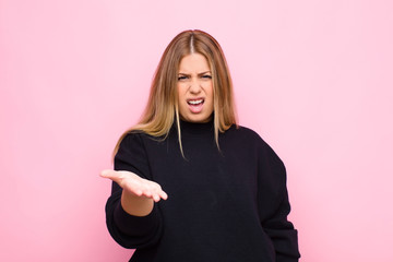 young blonde woman looking angry, annoyed and frustrated screaming wtf or what‚Äôs wrong with...