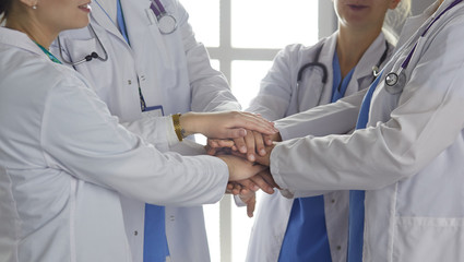 Team of medical workers holding hands together indoors, above view. Unity concept