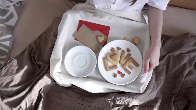 Woman have a romantic Breakfast in cozy morning bed. Coffee and word love from cookies. Surprise on Valentine's day