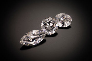 A marque, round and oval cut diamonds sit on a black sandblasted glass reflective background.