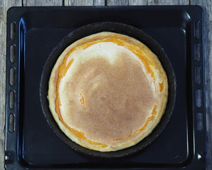 Round homemade pie with pumpkin, chopped walnuts, topped with beaten eggs with sugar in a pan in the oven for baking. Homemade baking.