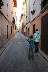 Fototapeta premium Młody fotograf z matką na wąskiej uliczce w starym hiszpańskim mieście
