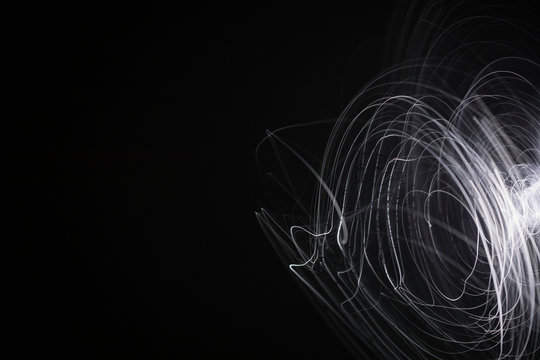 Creative, abstract spinning white spark on black background