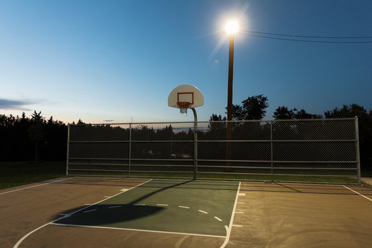 Basketball court lit by floodlight at night