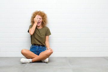 young afro woman laughing and slapping forehead like saying d‚Äôoh! I forgot or that was a...