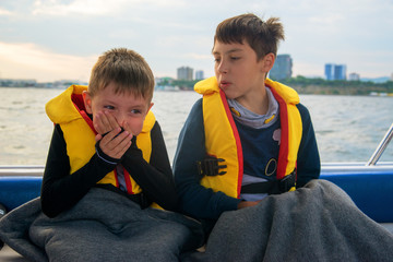 boy suffers from seasickness on board the boat, closes his mouth with his hands - obrazy, fototapety, plakaty