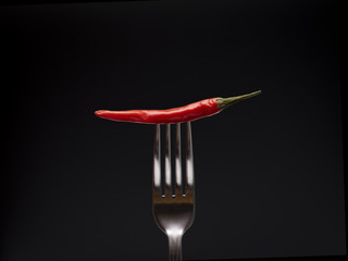 Chile on a fork on a black background