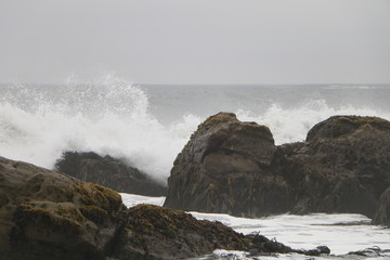 Fototapeta na wymiar olas reventando en rocas con día nublado en playa