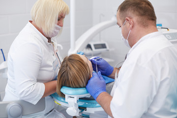 Obraz na płótnie Canvas Doctor dentist treats teeth of a beautiful young girl patient. The girl on reception at the dentist. Doctor dentist treats tooth