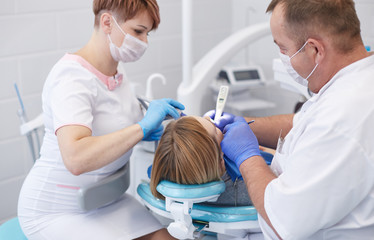 Obraz premium Doctor dentist treats teeth of a beautiful young girl patient. The girl on reception at the dentist. Doctor dentist treats tooth