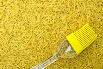 background with italian pasta vermicelli and yellow silicone kitchen brush or tassel with...