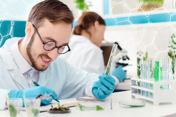 Scientists are working at microbiology laboratory. Man is writing results of experiments with...