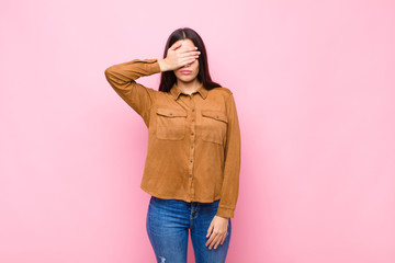 young pretty woman covering eyes with one hand feeling scared or anxious, wondering or blindly...