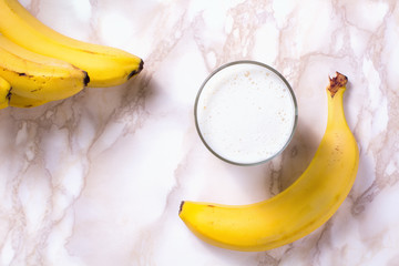 Glass of banana smoothie on marble table. Top view.
