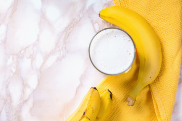 Glass of banana smoothie on marble table. Top view.