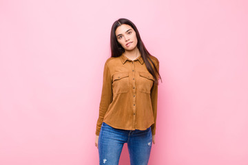 young pretty woman looking puzzled and confused, biting lip with a nervous gesture, not knowing the...
