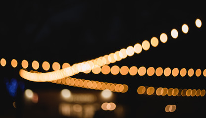 Decorative outdoor string lights at night time, Defocused Background, night city life backdrop, party time with Yellow bokeh balls