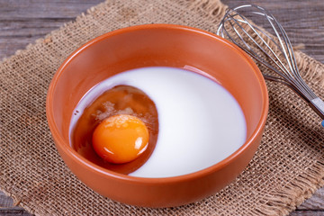Egg with milk in a deep bowl with a whisk